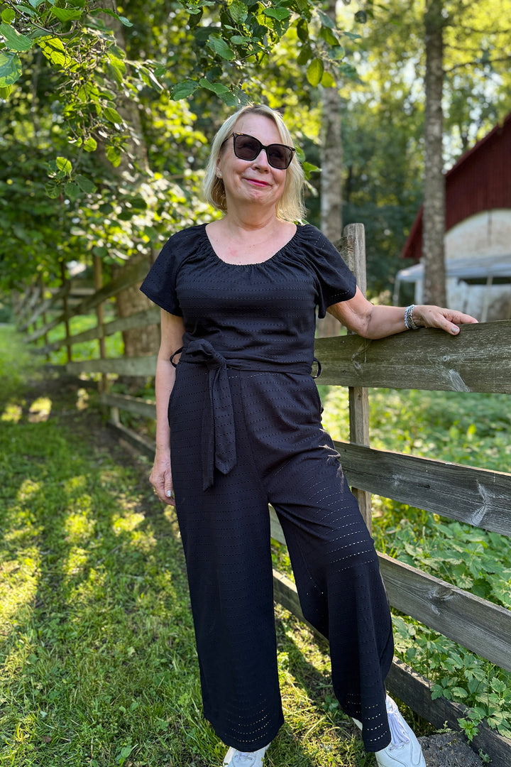 Jasmine- neuloshaalari koossa XS/S reikäraita-materiaalissa. Haalarissa on oma irtovyö, jonka voit halutessasi korvata toisella vyöllä.