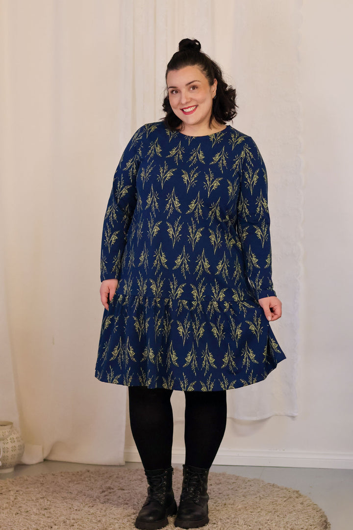 Tässä kauniissa a-linjaisessa mekossa on taskut sekä poimutettu helma. Mekko on valmistettu täysin Suomessa; materiaali on Orivedeltä, kuosi painettu Pälkäneellä ja ommeltu Tampereella.