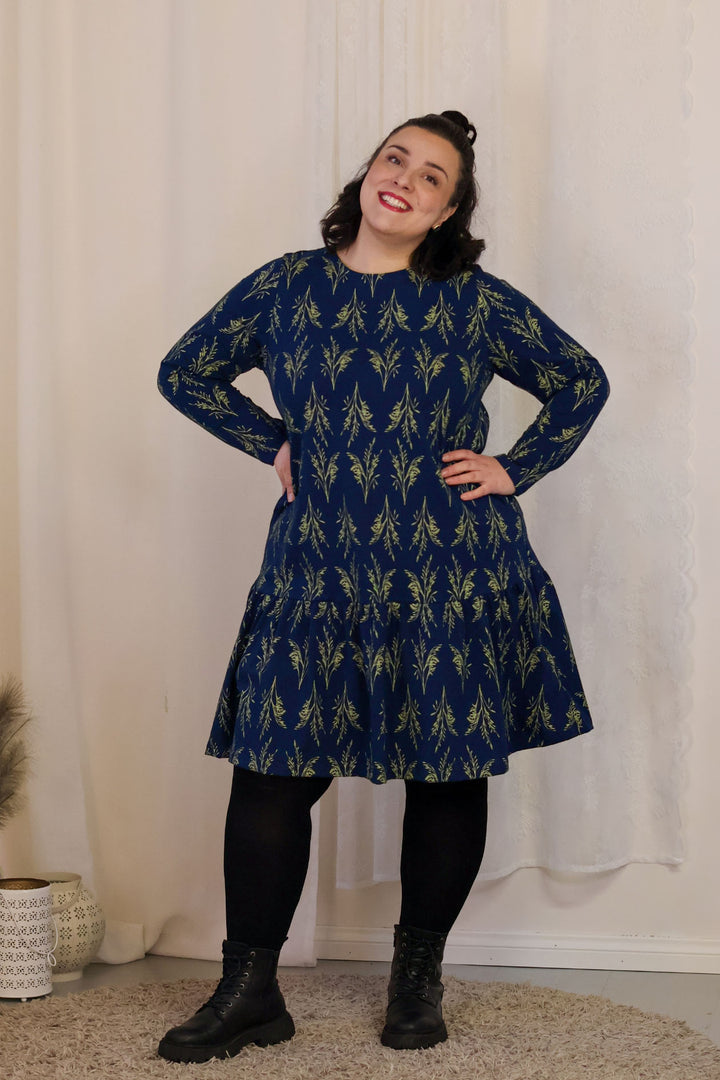 Juni-neulosmekko Vilja-kuosilla koossa XL. Mekko on a-linjainen ja siinä on poimutettu helma sekä taskut.