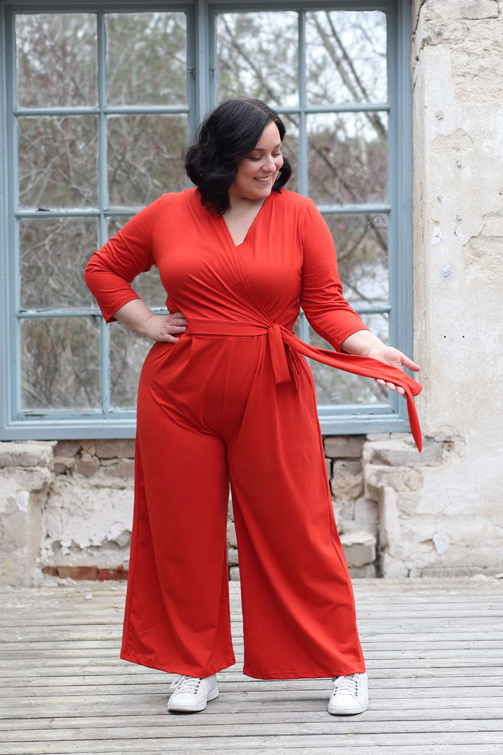 Punaisenoranssi Madeline-kietaisuhaalari koossa XXL. Jumpsuitissa on pitkät nauhat, jotka voi sitoa monella eri tapaa. Haalarissa on pitkät leveät lahkeet.
