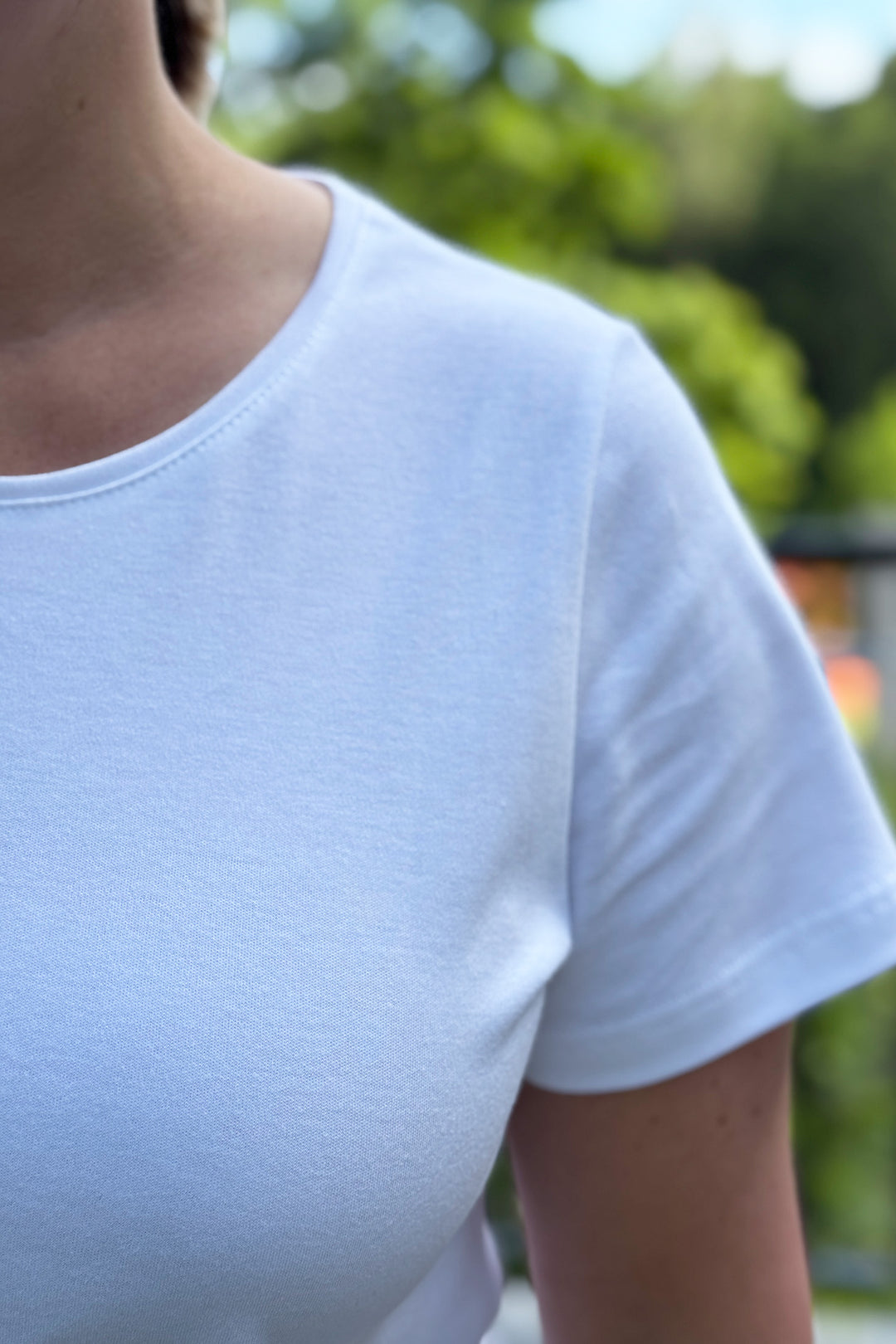 Lähikuva valkoisesta t-paidasta. Paidassa on kaunis pääntie.